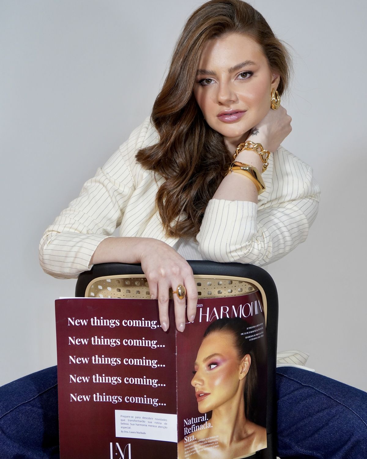 Dra. Laura Machado sentada, segurando uma revista com a marca LM